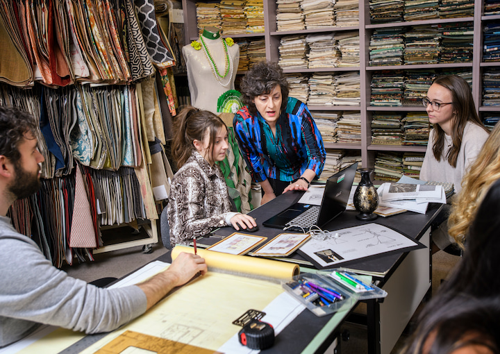Students with a professor in room full of fabric