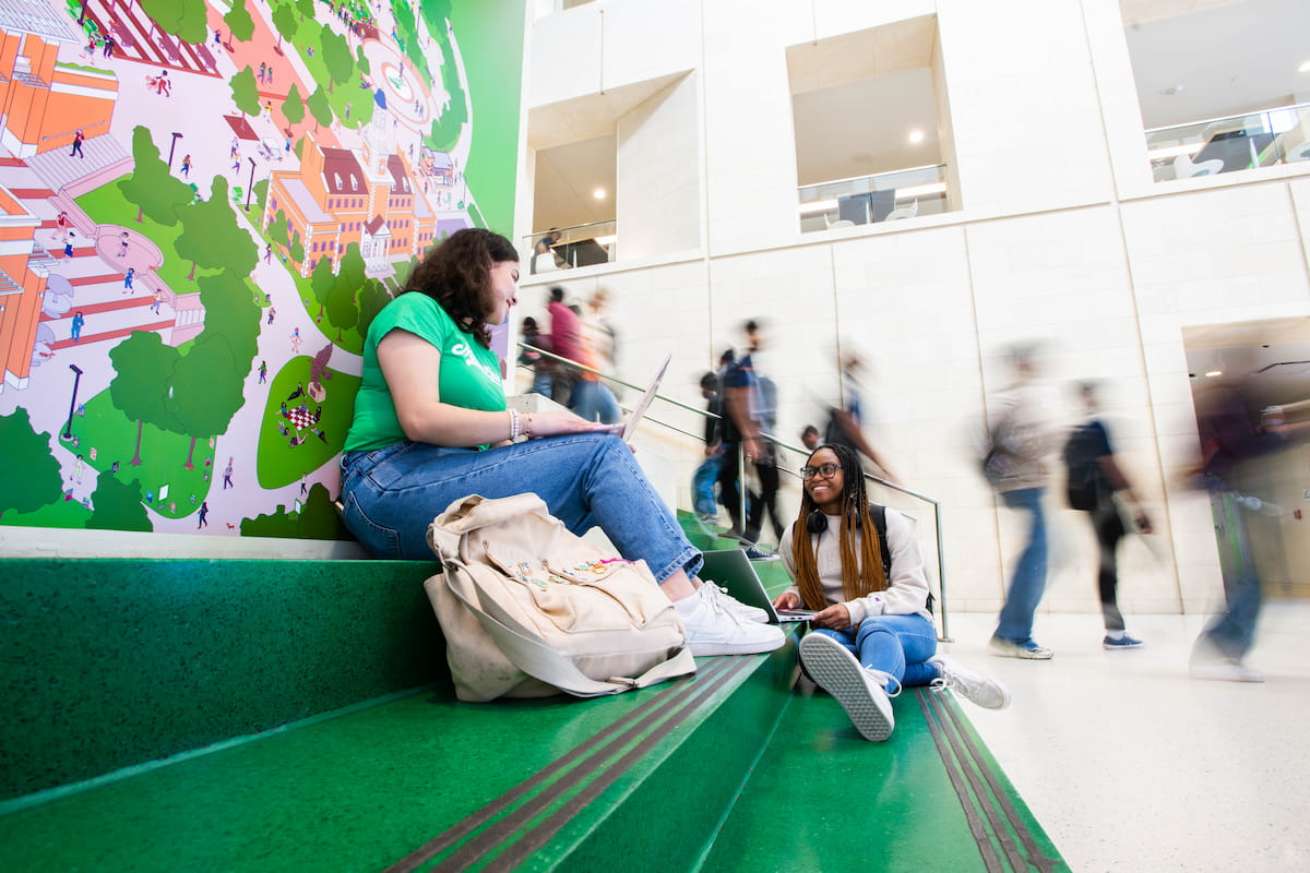 Student sits on green stairs in the Union